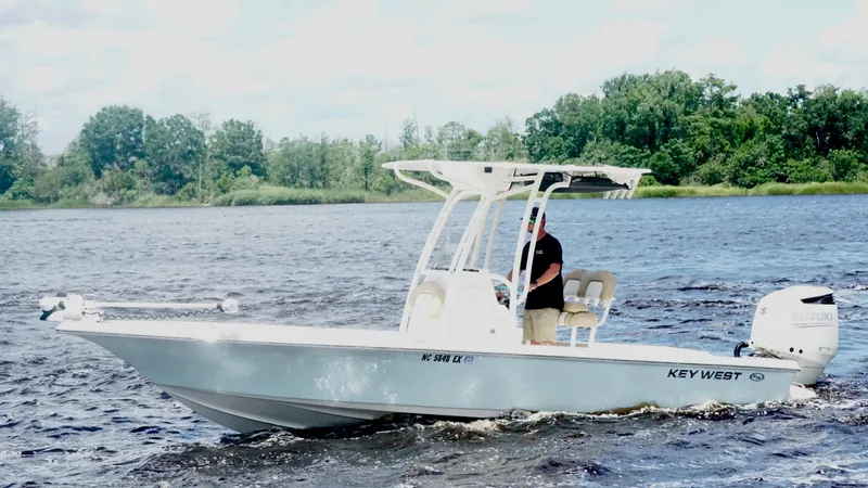 Slide: The Image of 2018 Key West 230 Bay Reef boat cruising on a lake with lush green shoreline. - 2