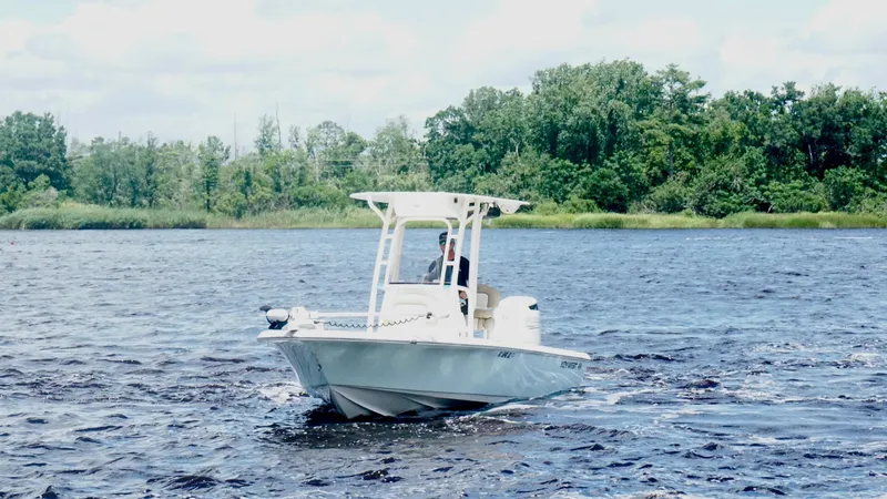 Slide: The Image of 2018 Key West 230 Bay Reef boat cruising on a scenic lake with lush green trees. - 7