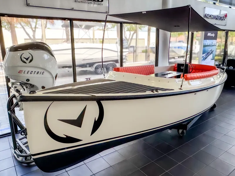 Slide: The Image of 2024 Vision Marine Technologies Fantail 217 electric boat with canopy and red seating in showroom. - 1