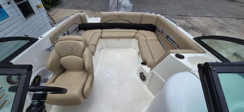 Slide: The Image of 2019 NauticStar 223DC Sport Deck boat interior with beige seating and steering wheel. - 14