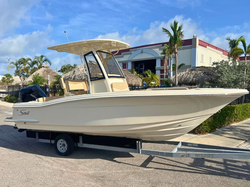 Slide: The Image of 2025 Scout 215 XSF boat on trailer, parked outdoors under clear sky. - 0