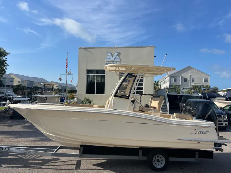 Slide: The Image of 2025 Scout 215 XSF boat on trailer, parked outside dealership under clear blue sky. - 1