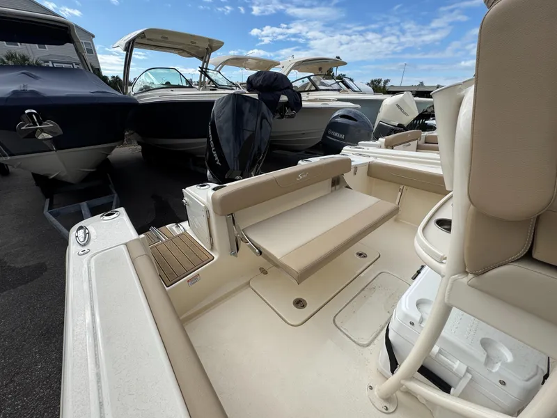 Slide: The Image of 2025 Scout 215 XSF boat interior with seating and motor, under a clear blue sky. - 12