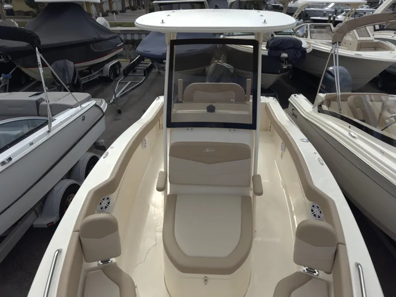 Slide: The Image of 2025 Scout 215 XSF boat with beige interior, docked among other boats. - 5