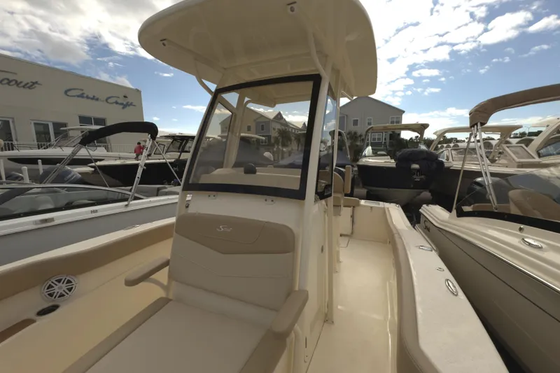 Slide: The Image of 2025 Scout 215 XSF boat with center console, docked under a partly cloudy sky. - 6