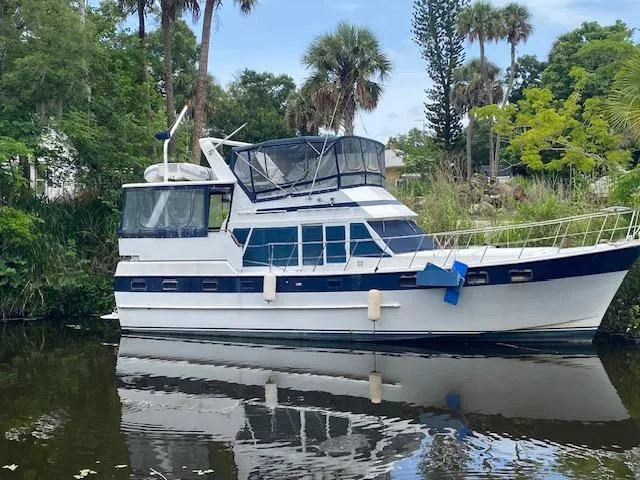 The Image of 1984 Nova Trawler Heritage boat docked on a calm river, surrounded by lush greenery. - 0