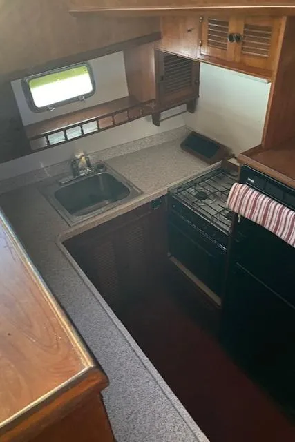 Slide: The Image of 1984 Nova Trawler Heritage kitchen with sink, stove, and wooden cabinetry. - 14