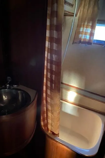 Slide: The Image of 1984 Nova Trawler Heritage bathroom with sink, shower, and checkered curtain. - 15