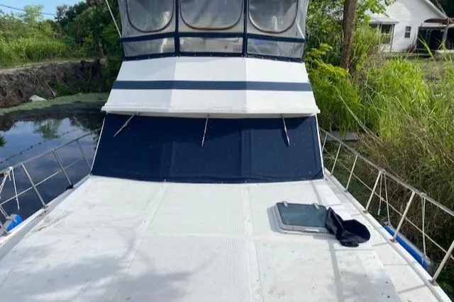 Slide: The Image of 1984 Nova Trawler Heritage boat deck with canopy, surrounded by lush greenery. - 2