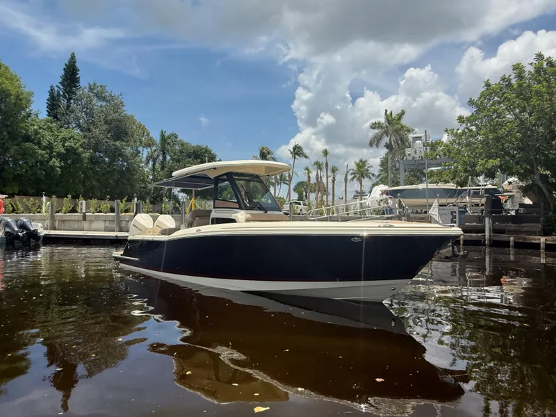 Slide: The Image of 2025 Chris-Craft Catalina 28 boat docked on a sunny day with lush greenery. - 2