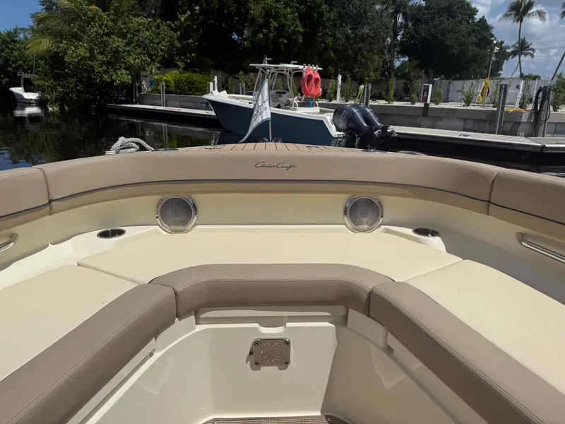 Slide: The Image of 2025 Chris-Craft Catalina 28 boat interior with beige seating and speakers, docked by lush greenery. - 28