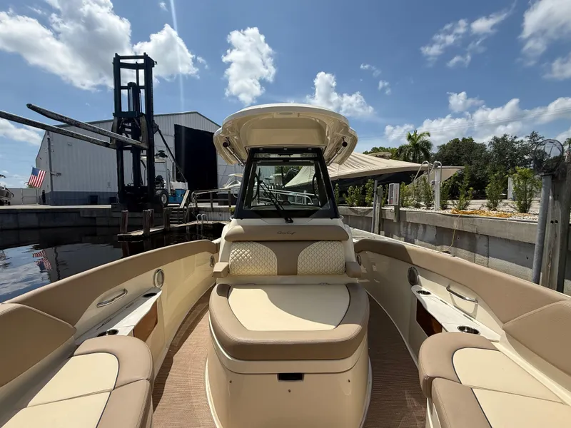 Slide: The Image of 2025 Chris-Craft Catalina 28 boat interior with beige seating, docked under a sunny sky. - 33