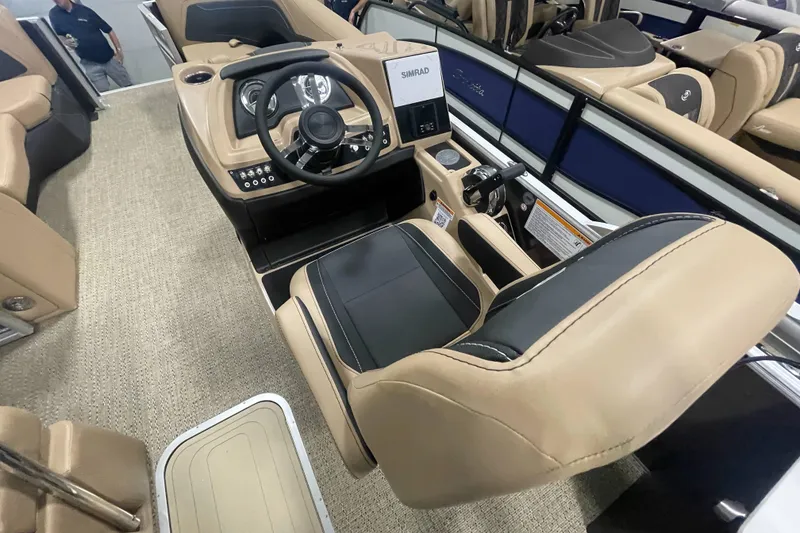 Slide: The Image of 2026 Barletta Cabrio 24UE boat interior with beige and black seating, steering console, and Simrad display. - 10