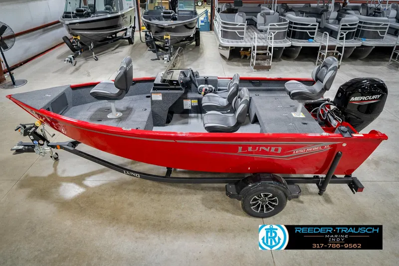The Image of 2026 Lund 1650 Rebel XL SS boat in showroom, featuring red exterior and Mercury engine. - 0