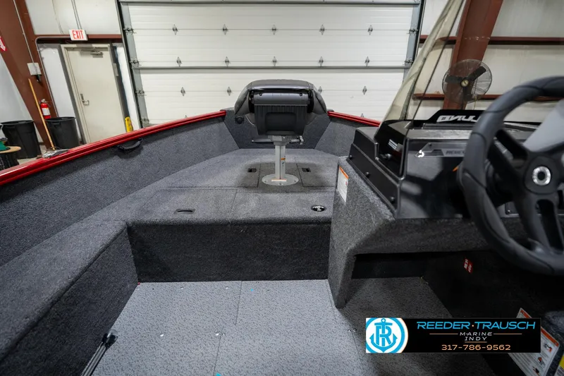 Slide: The Image of 2026 Lund 1650 Rebel XL SS boat interior with steering wheel and seating in a garage. - 15