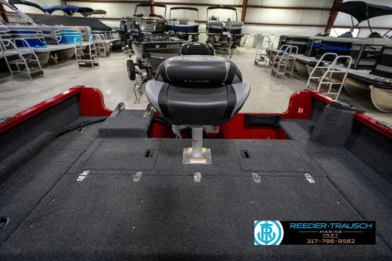 Slide: The Image of 2026 Lund 1650 Rebel XL SS boat interior in showroom, featuring seating and storage. - 19