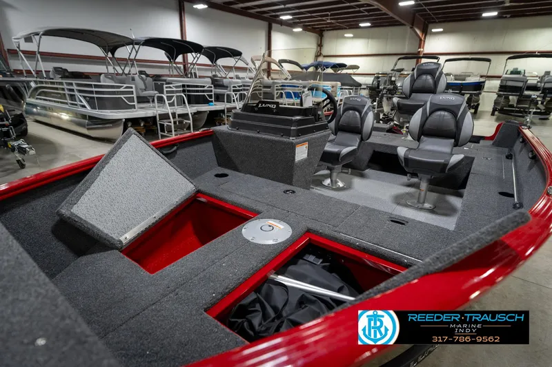Slide: The Image of 2026 Lund 1650 Rebel XL SS boat interior with seating and storage, displayed in a showroom. - 22