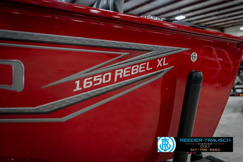 Slide: The Image of Red 2026 Lund 1650 Rebel XL SS boat with sleek graphics, displayed indoors. - 49