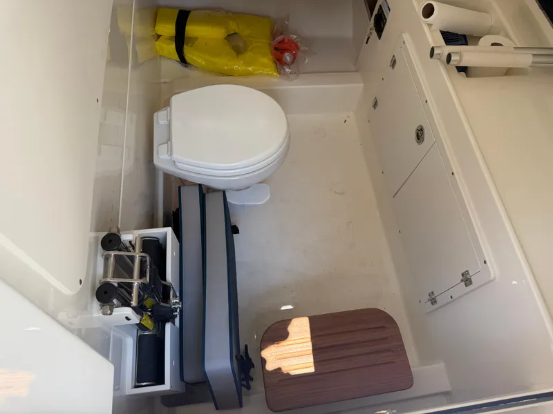 Slide: The Image of 2024 Boston Whaler 330 Outrage interior with toilet, life jacket, and storage compartments. - 10