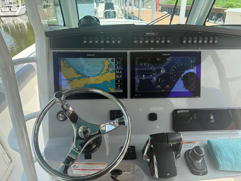 Slide: The Image of 2024 Boston Whaler 330 Outrage helm with dual Simrad displays and steering wheel. - 15