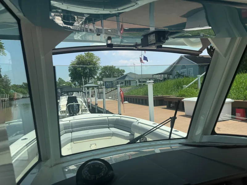 Slide: The Image of 2024 Boston Whaler 330 Outrage docked, viewed from the helm, with scenic waterfront backdrop. - 16