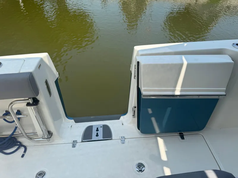 Slide: The Image of 2024 Boston Whaler 330 Outrage boat with open transom door, docked on calm water. - 17