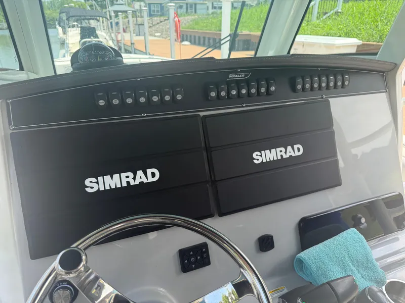 Slide: The Image of 2024 Boston Whaler 330 Outrage helm with dual Simrad displays and steering wheel. - 19