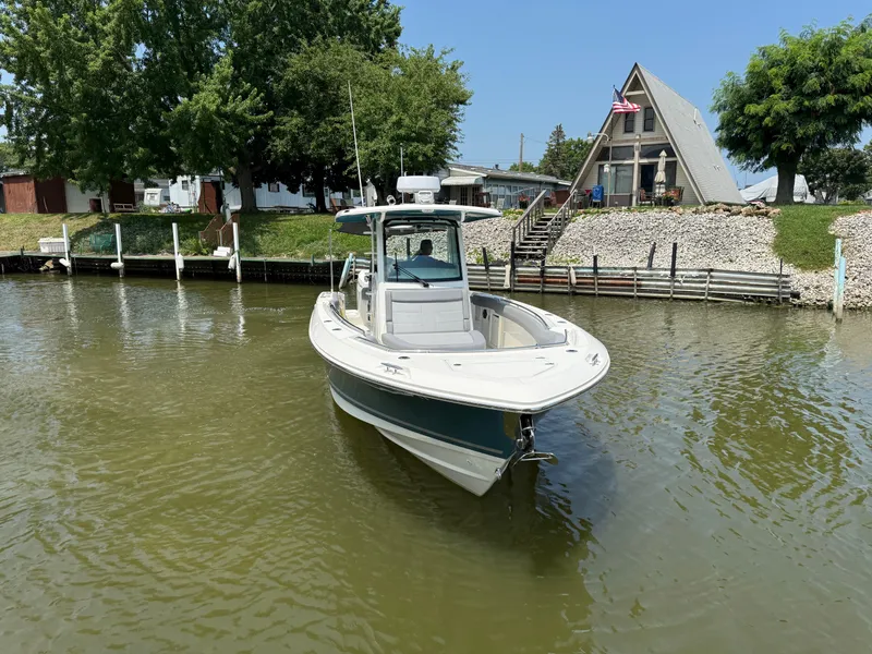 Slide: The Image of 2024 Boston Whaler 330 Outrage boat docked near a lakeside house with trees. - 3