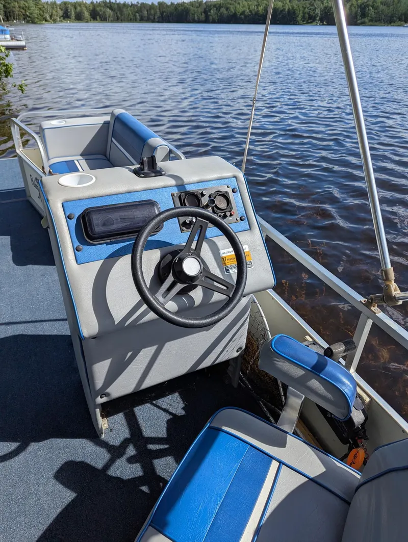 Slide: The Image of 1991 Palm Beach Super 220 boat interior with steering wheel, blue and gray seating, on a lake. - 3