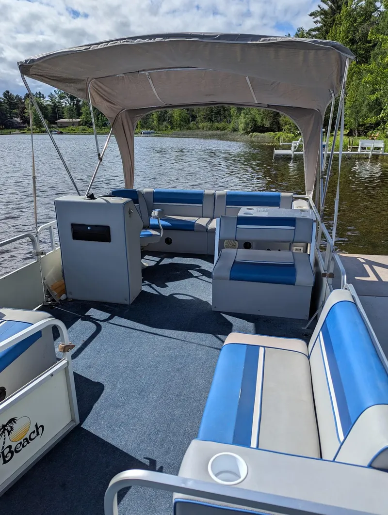 Slide: The Image of 1991 Palm Beach Super 220 pontoon boat with blue seating, canopy, and lake view. - 4