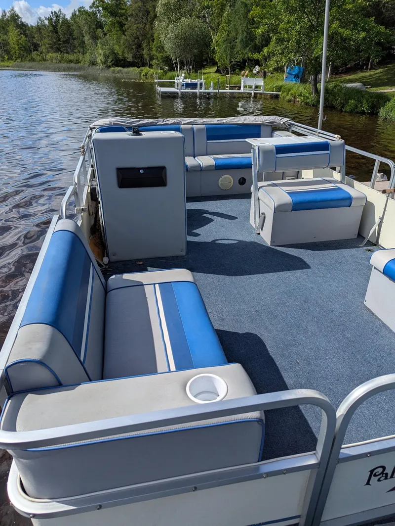 Slide: The Image of Pontoon boat with blue seating, Palm Beach Super 220, 1991, on a serene lake. - 6