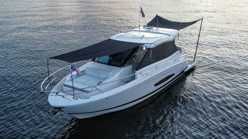Slide: The Image of 2021 Regal 36 Grande Coupe yacht on calm water, featuring sleek design and sunshade. - 12