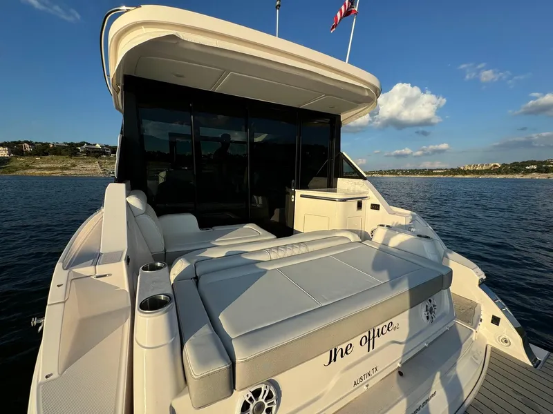 Slide: The Image of 2021 Regal 36 Grande Coupe yacht on water, rear view with seating and American flag. - 16