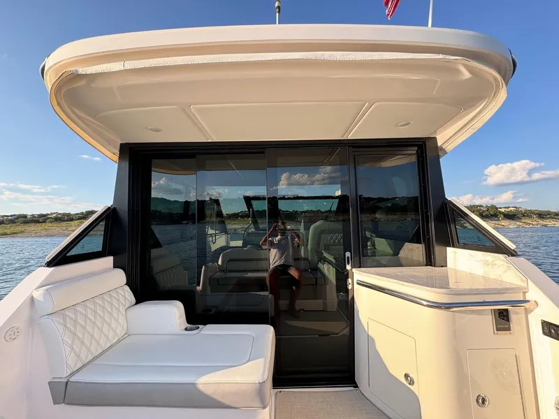 Slide: The Image of 2021 Regal 36 Grande Coupe yacht with seating area and glass doors on a sunny day. - 18