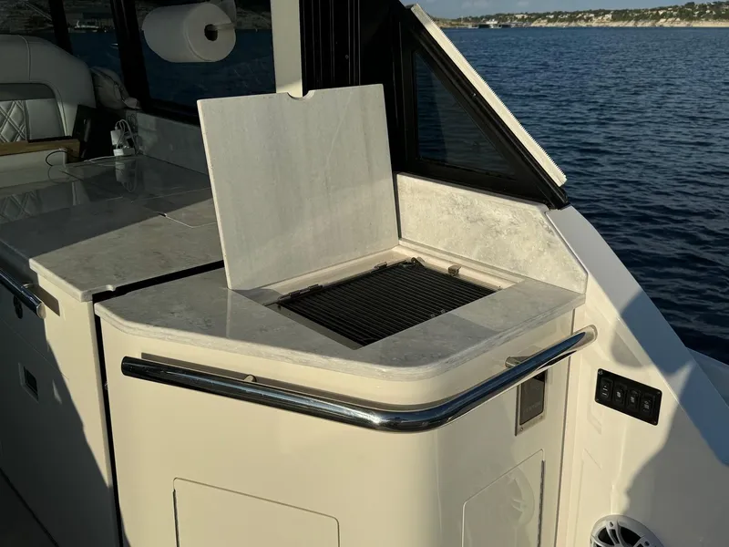 Slide: The Image of Outdoor grill on 2021 Regal 36 Grande Coupe yacht, overlooking serene water. - 20