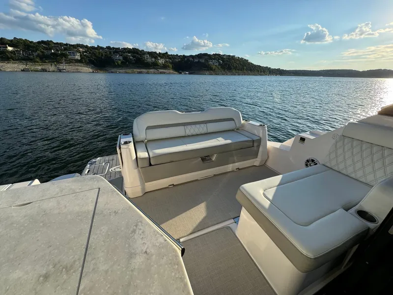 Slide: The Image of 2021 Regal 36 Grande Coupe boat interior with luxurious seating on a serene lake. - 21