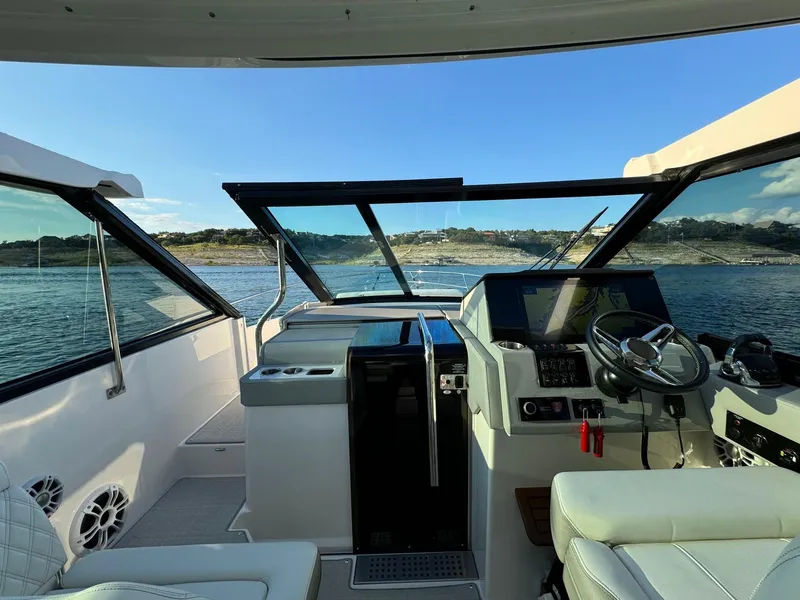 Slide: The Image of 2021 Regal 36 Grande Coupe cockpit with modern controls, steering wheel, and scenic water view. - 29