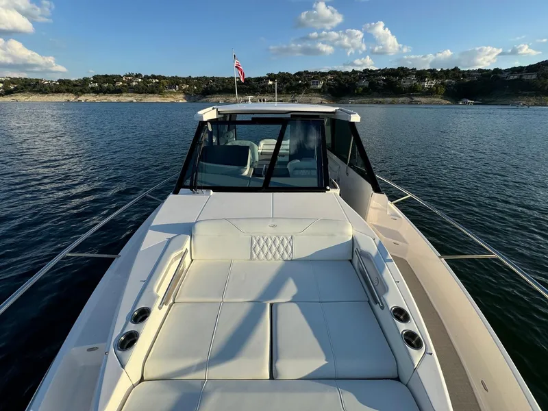 Slide: The Image of 2021 Regal 36 Grande Coupe on serene water, showcasing luxurious deck seating and scenic shoreline. - 35