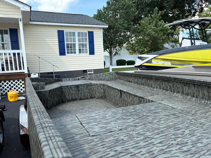 Slide: The Image of 2025 Edge Duck Boats Standard 656DB with camouflage design, parked near a house and yellow boat. - 6