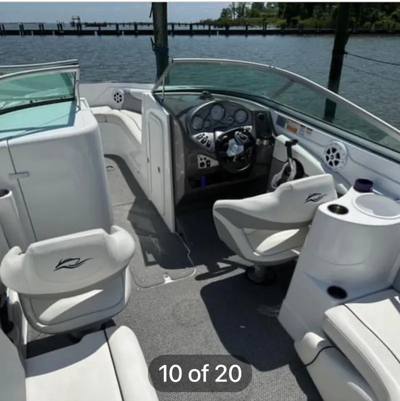 Slide: The Image of 2015 Rinker 246 Captiva Bowrider interior with steering wheel and seating, docked by the water. - 6