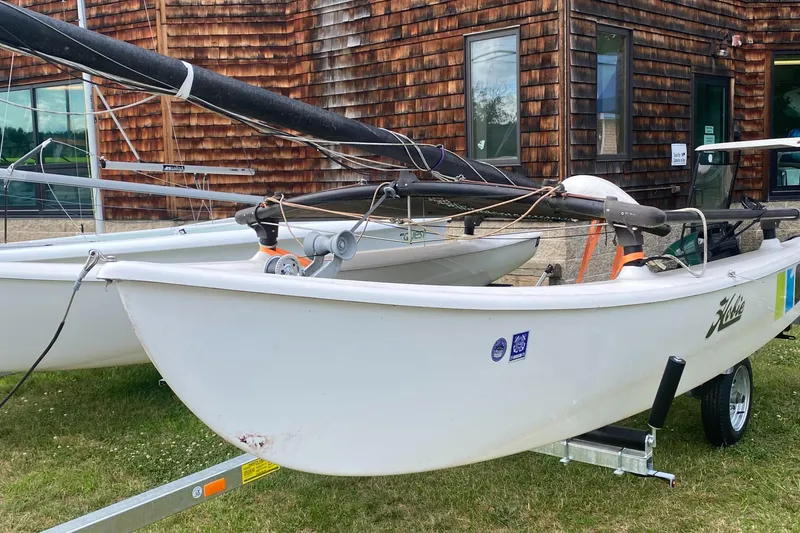 Slide: The Image of 2017 Hobie 16 catamaran on trailer, parked on grass near wooden building. - 3
