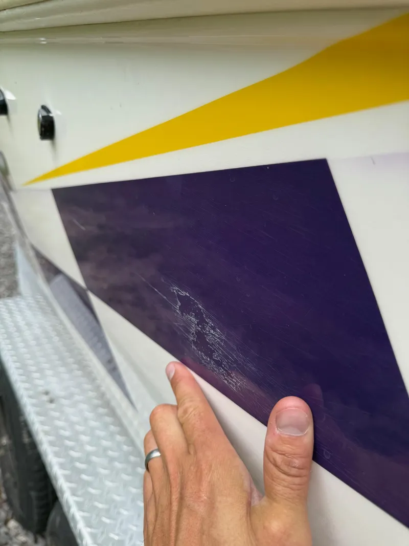 Slide: The Image of Close-up of 1999 Donzi 26 ZX boat with yellow and purple graphics, showing surface scratches. - 11