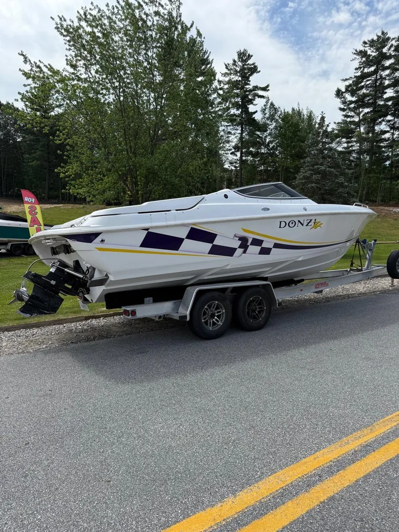 Slide: The Image of 1999 Donzi 26 ZX boat on trailer, parked on roadside with trees in background. - 4