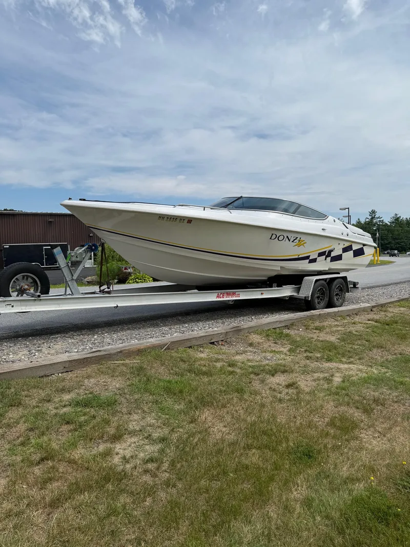 Slide: The Image of 1999 Donzi 26 ZX boat on trailer, parked outdoors under a cloudy sky. - 9