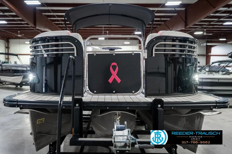 Slide: The Image of 2019 Avalon Ambassador 27' pontoon boat with pink ribbon, displayed indoors at Reeder-Trausch Marine. - 5