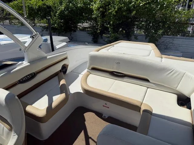 Slide: The Image of 2020 Cobalt CS23 boat interior with white and tan seating, lush greenery in the background. - 16