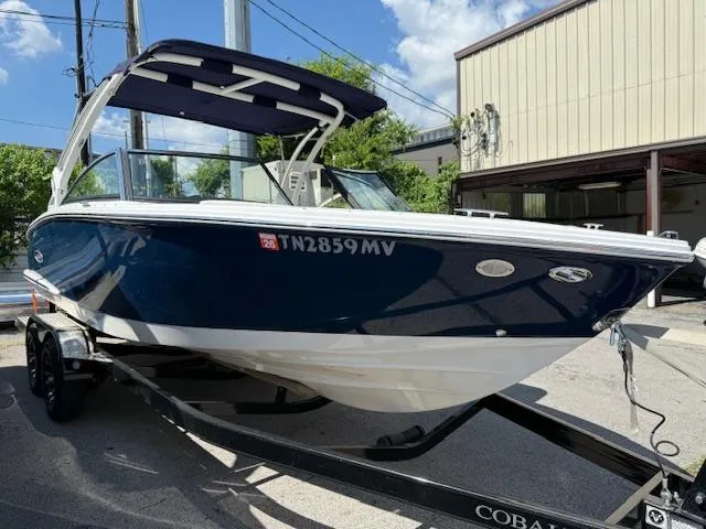 Slide: The Image of 2020 Cobalt CS23 boat on trailer, blue and white, parked outdoors. - 3