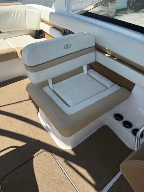 Slide: The Image of 2020 Cobalt CS23 boat interior with beige and white seating, cup holders, and carpeted flooring. - 7