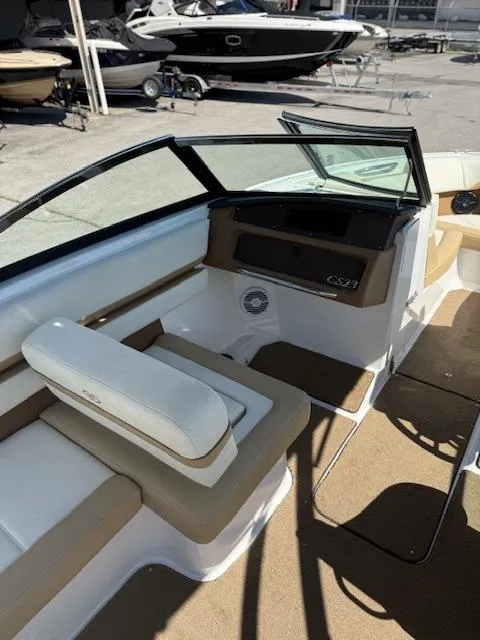 Slide: The Image of 2020 Cobalt CS23 boat interior with beige seating and dashboard, parked in a marina. - 8