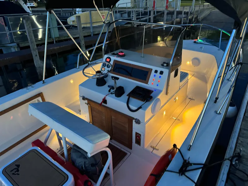 Slide: The Image of 1987 Custom Biddison 2200 boat interior with illuminated dashboard and seating at dock. - 16